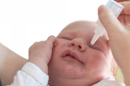 Eye dropper administering eye drops to baby